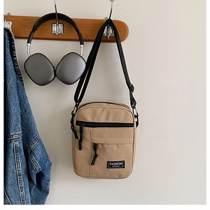 Detail of khaki canvas crossbody bag featuring Fashion Instinct label and zipper pocket