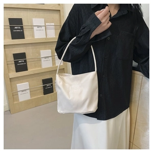 Detail of minimalist cream nylon tote bag with black embroidery on stylish shoulder strap