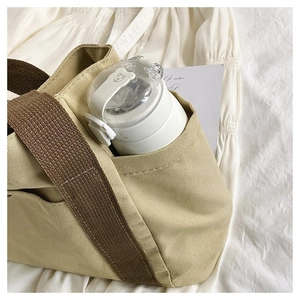 Detail view of the beige canvas tote bag with side pocket for water bottle and brown straps