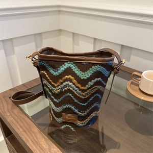 Close-up of brown knit bucket bag featuring colorful wave patterns and leather logo patch