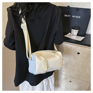 Detail of a cylindrical cream and light blue nylon crossbody bag with buckle straps