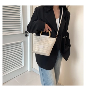 Sac seau tressé beige chic avec poignées anneaux sur un mannequin féminin