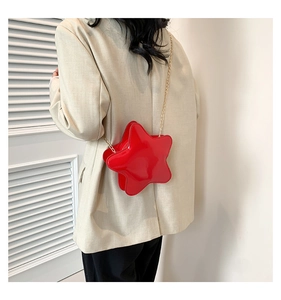 Mini sac étoile en cuir verni rouge avec bandoulière chaîne sur blazer blanc