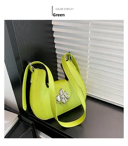 Détail du sac bandoulière demi-lune vert avec un fermoir floral en métal argenté trèfle