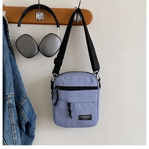 Vertical lavender canvas mini crossbody bag with black adjustable strap and fashion label