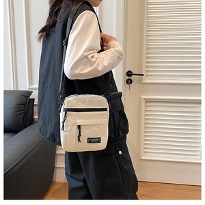Detailed shot of white vertical mini crossbody bag featuring a front zipper and drawcord