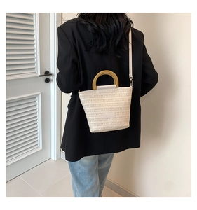 Détail du sac seau tissé avec poignées rondes en bois et bandoulière beige clair