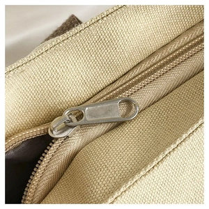 Close-up of durable beige canvas tote bag showing silver metal zipper detail and texture