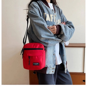 Detail view of a red canvas crossbody phone bag showing the fashion label on a model
