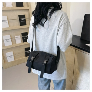 Detail view of black canvas crossbody bag featuring adjustable double buckle straps for utility
