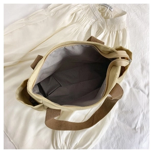 Detail of canvas tote bag interior with gray lining, zipper closure, and side pocket