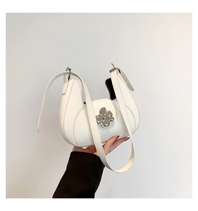 Détail d'un sac demi-lune blanc avec fermoir fleur argentée et bandoulière réglable