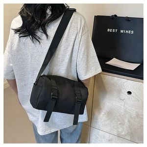 Detail view of black nylon messenger bag featuring adjustable straps and buckle closures