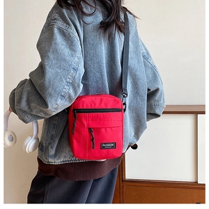 Close-up of a red nylon mini crossbody bag with Fashion Instinct label worn by a model