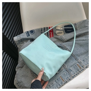 Close-up of mint green nylon tote bag with embossed text on blue denim background