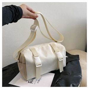 Detail of cylinder crossbody bag featuring durable nylon fabric and white plastic buckle