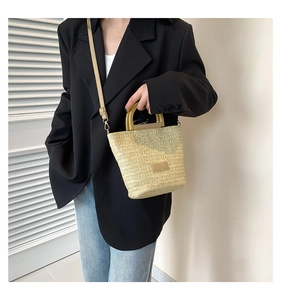 Sac seau tissé beige tendance avec poignée en bois porté par un mannequin en tailleur