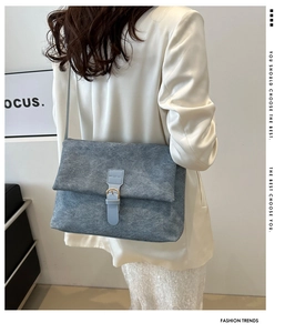 Vue détaillée du sac à bandoulière en feutre bleu mat avec une boucle en cuir élégante et moderne