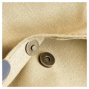 Macro detail of the bronze magnetic closure and heavy canvas texture of the tote bag