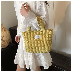 Détail de la texture matelassée à bulles et étiquette Love Fashion sur le sac jaune
