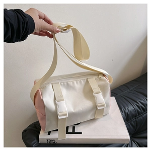 Detail of the cylindrical crossbody bag showing durable nylon fabric and plastic buckle