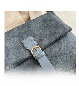 Gros plan du sac en cuir nubuck gris avec sangle bleue et boucle dorée chic