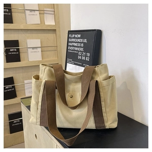 Detail view of large canvas tote bag with brown straps and functional external pockets