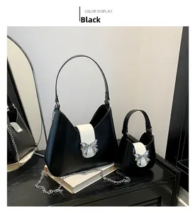 Detail view of two black and white saddle bags with metallic bow clasps and chain straps