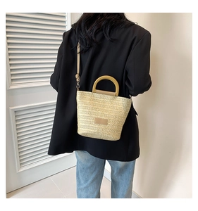 Détail du sac cabas en paille tissée avec poignées rondes en bois et bandoulière réglable