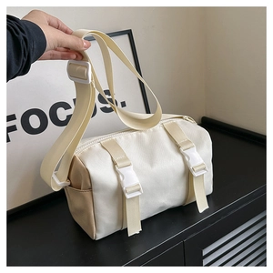 Detail view of the cream white crossbody bag with white buckles and brown side panel