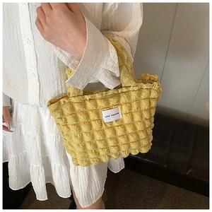 Détail du sac cabas en tissu popcorn jaune avec volants texturés et étiquette de marque