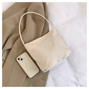 Detail shot of beige nylon underarm bag featuring pretty and liberty letter embroidery