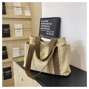 Close-up of beige canvas tote bag showing thick fabric texture and brown handles