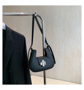 Détail du sac demi-lune noir mat orné d'une grande boucle en forme de fleur argentée