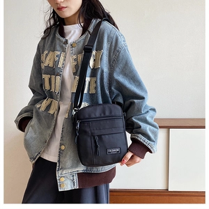 Close-up of black crossbody bag with adjustable strap and Fashion label on a model