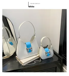 White saddle bag set with blue straps, silver bow details and metallic chains