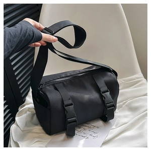 Detail of black nylon cylindrical crossbody bag featuring plastic buckles and zipper closure