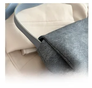 Détail du sac bandoulière gris mat avec sangle en cuir bleu et coutures précises