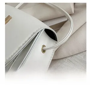 Detailed close-up of white leather texture and gold metal ring on a small square bag