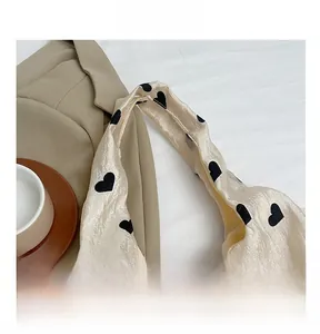 Close-up of beige tote bag with black heart pattern on textured fabric with blazer