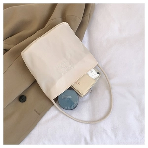 Close-up of minimalist cream nylon tote bag interior with everyday essentials inside