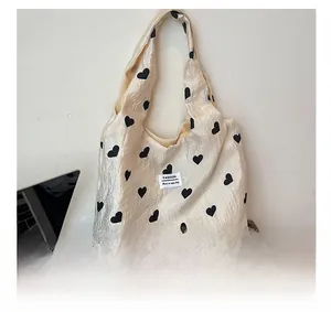 Macro shot of beige heart print tote bag with woven fashion label and textured fabric detail