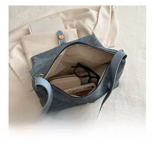 Vue macro montrant l'intérieur spacieux du sac cabas bleu avec portefeuille et lunettes