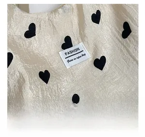 Close-up of champagne nylon tote bag featuring black heart patterns and fashion logo label