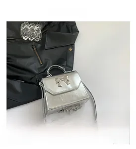 Detailed view of silver metallic square crossbody bag with bow-knot buckle and long strap