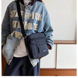Vertical black nylon crossbody mini bag worn by a model in a casual lifestyle setting