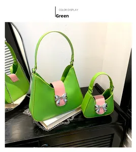 Detail of green and pink saddle bag set with silver bow accent and polished metal chain