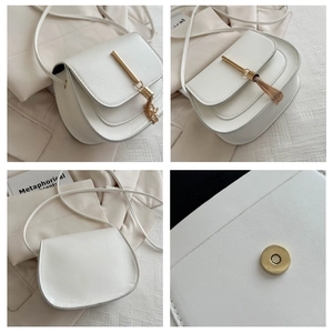 Detail of white PU leather saddle bag featuring golden tassel and magnetic buckle closure