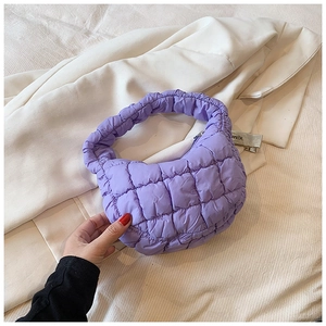 Close-up of quilted lilac nylon puff bag texture on a neutral blazer background