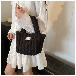 Détail du sac à main noir texturé bulle avec étiquette Love Fashion sur robe blanche